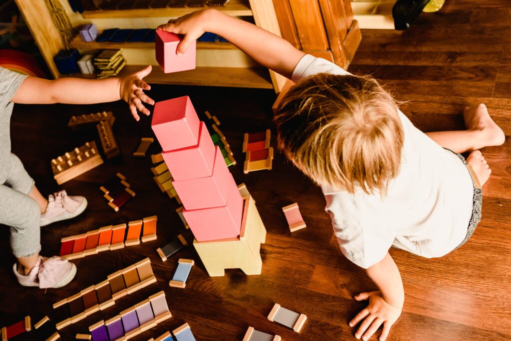enfant qui joue avec une tour rose montessori
